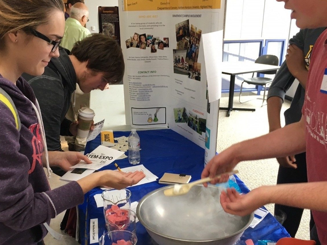 Students participating in a science activity at a STEM Expo booth