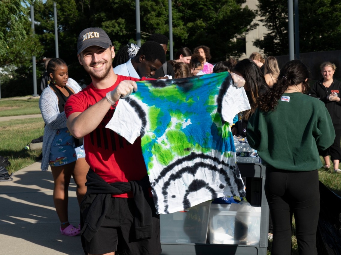 A STEM student happily displays the custom tie-dyed t-shirt they made at the STEM Tie-dye event.