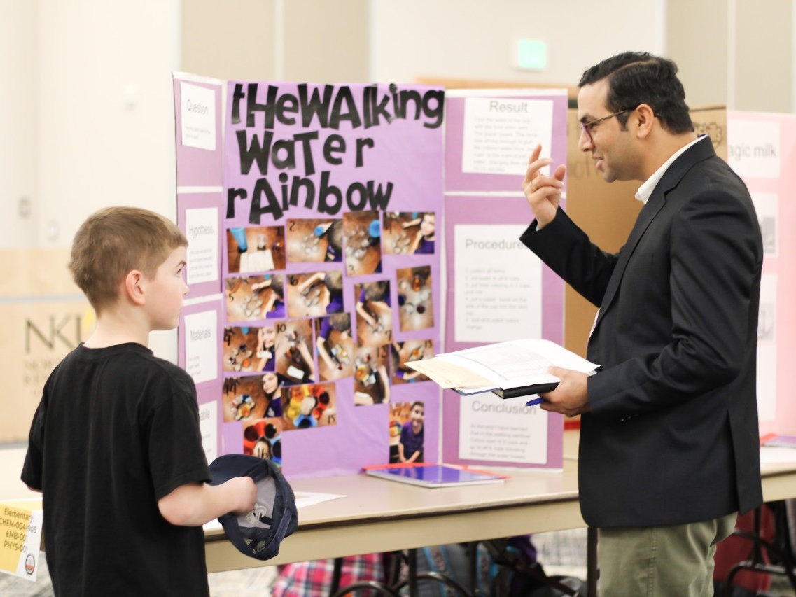A school-aged student presenting their poster and research to a SEFNK judge.