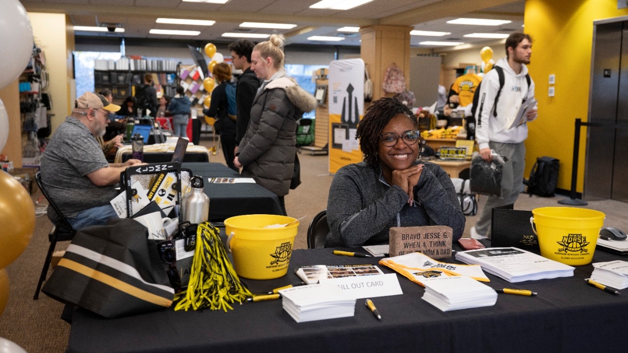 Woman smiling at a booth during Grad Fair