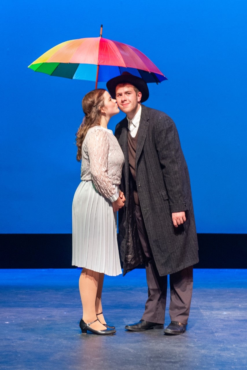 Girl kissing cheek of man under an umbrella