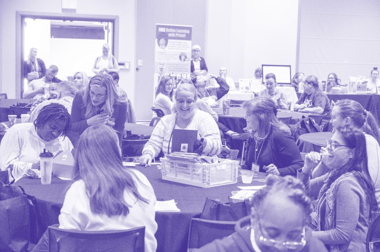 Conference attendees smile and mingle while looking at their raffle prizes.