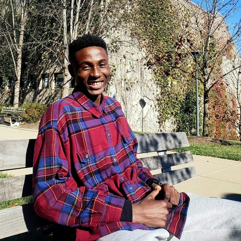Joshua Osakwe sitting on a bench outside
