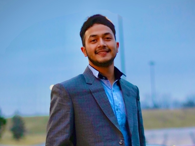 Binayak Shrestha smiling for the camera outside on campus.