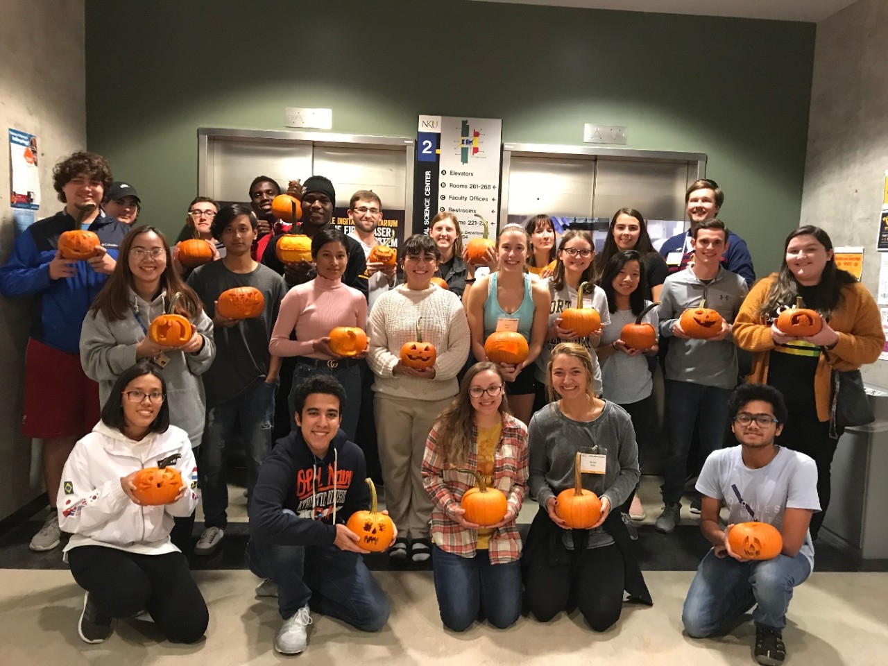 STEM students posing with their carved pumpkins at a pumpkin carving event