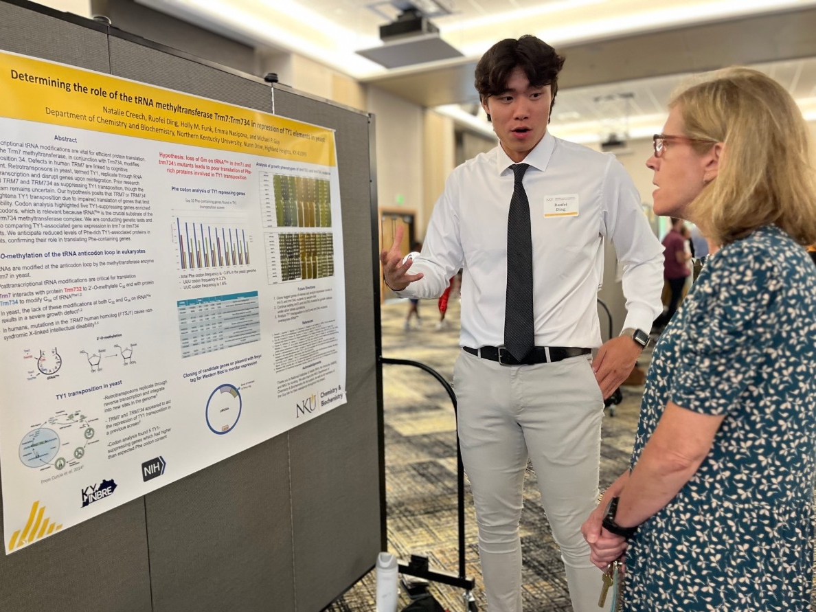 A STEM major presents their research poster to an event visitor