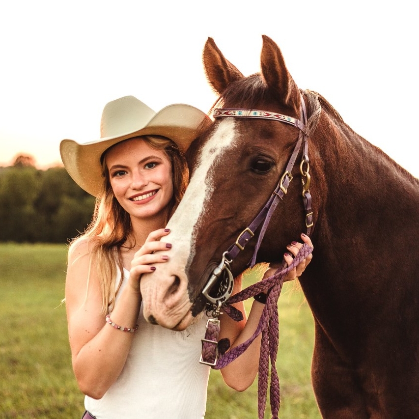 Alisha Detmer smiling standing next to her horse