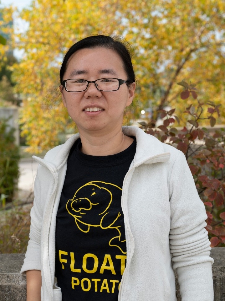 Photo of Dr. Xie outside against a backdrop of vibrant, autumn foliage.