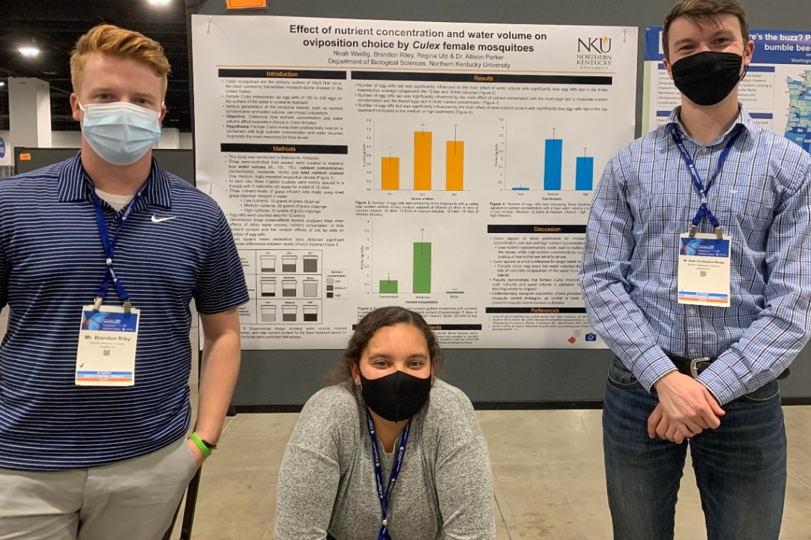 Three students smile for the camera in front of their award-winner undergraduate poster at the Entomological Society of America meeting