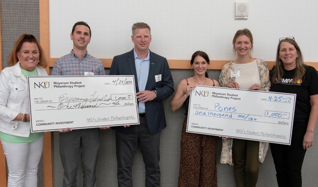 PAD 500 students with Julie Olberding holding large checks at the Mayerson ceremony