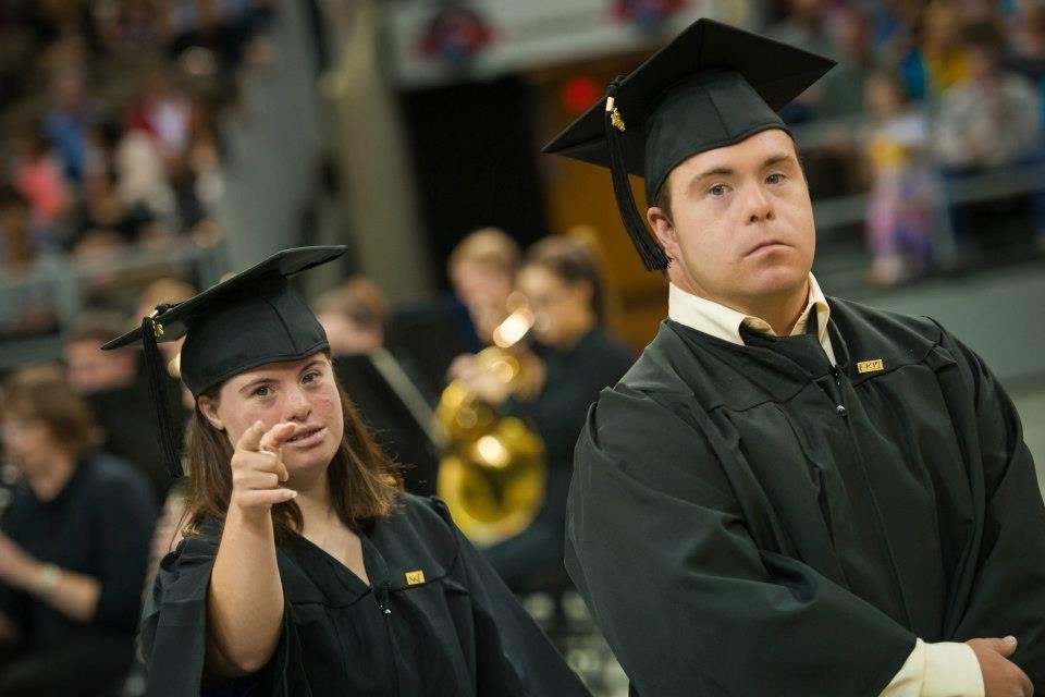 Two Shep students wearing graduation robes walking at NKU's commencement ceremony.