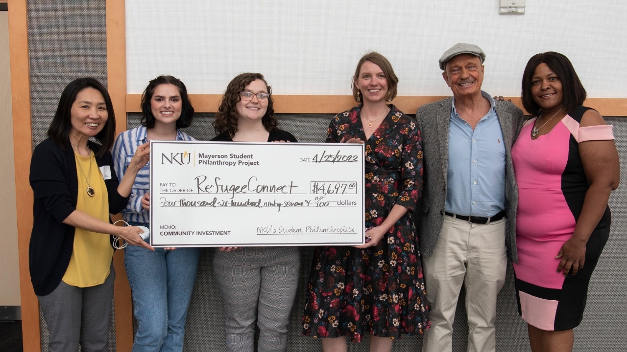 Students hold a large check to donate to a nonprofit organization