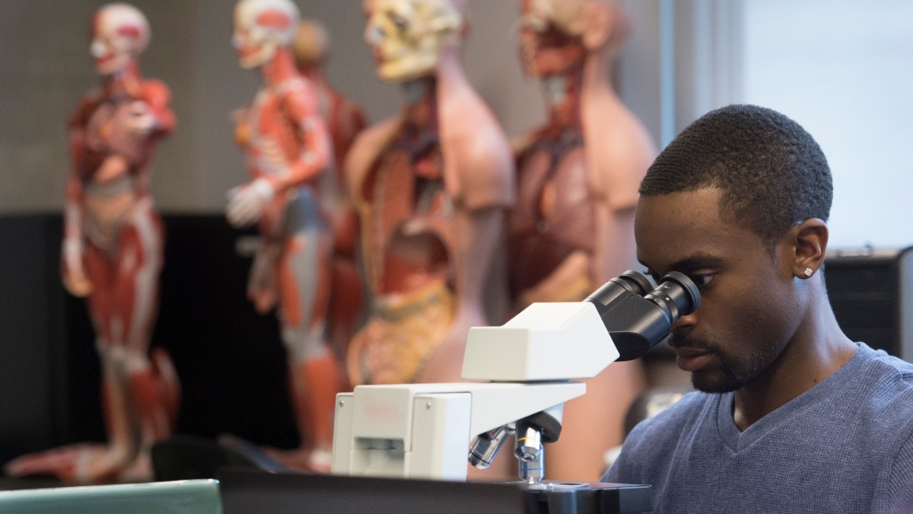 Male student of color at a microscope 