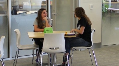 Two people have a conversation while sitting at a table