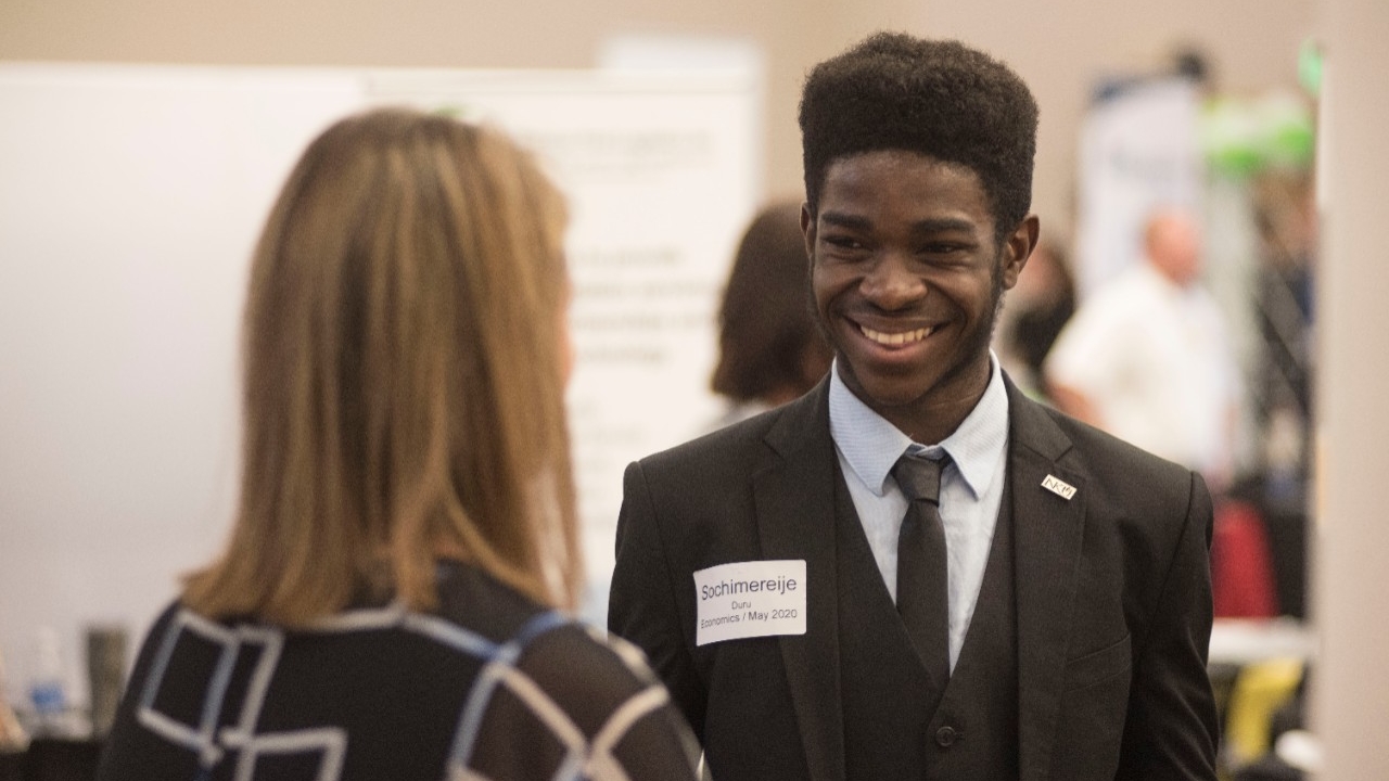 A student is greeted by a career fair attendee