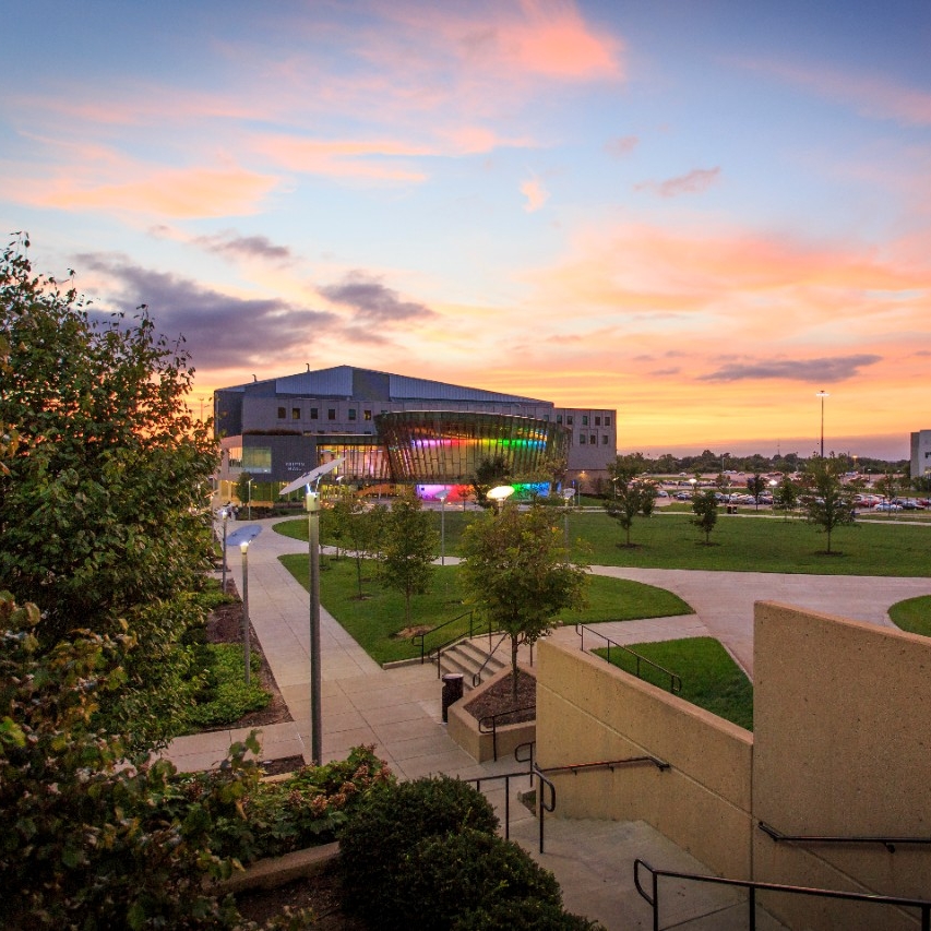 NKU Campus at sunset, highlighted is Griffin Hall lit up with colorful lights.