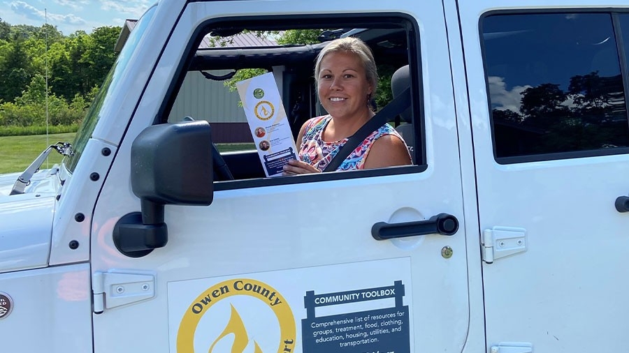 Shanna Osborne in jeep with brochure on Owen County Recovery Services resources.