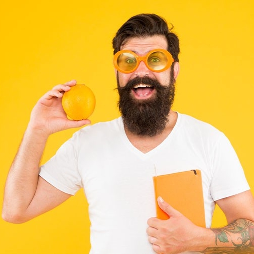 Bearded man holding book and orange fruit