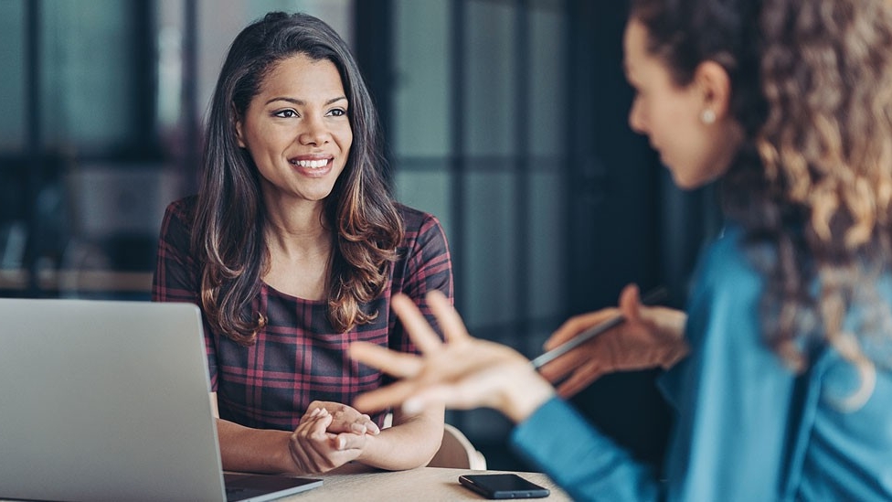 Two people discuss business while looking at a laptop computer