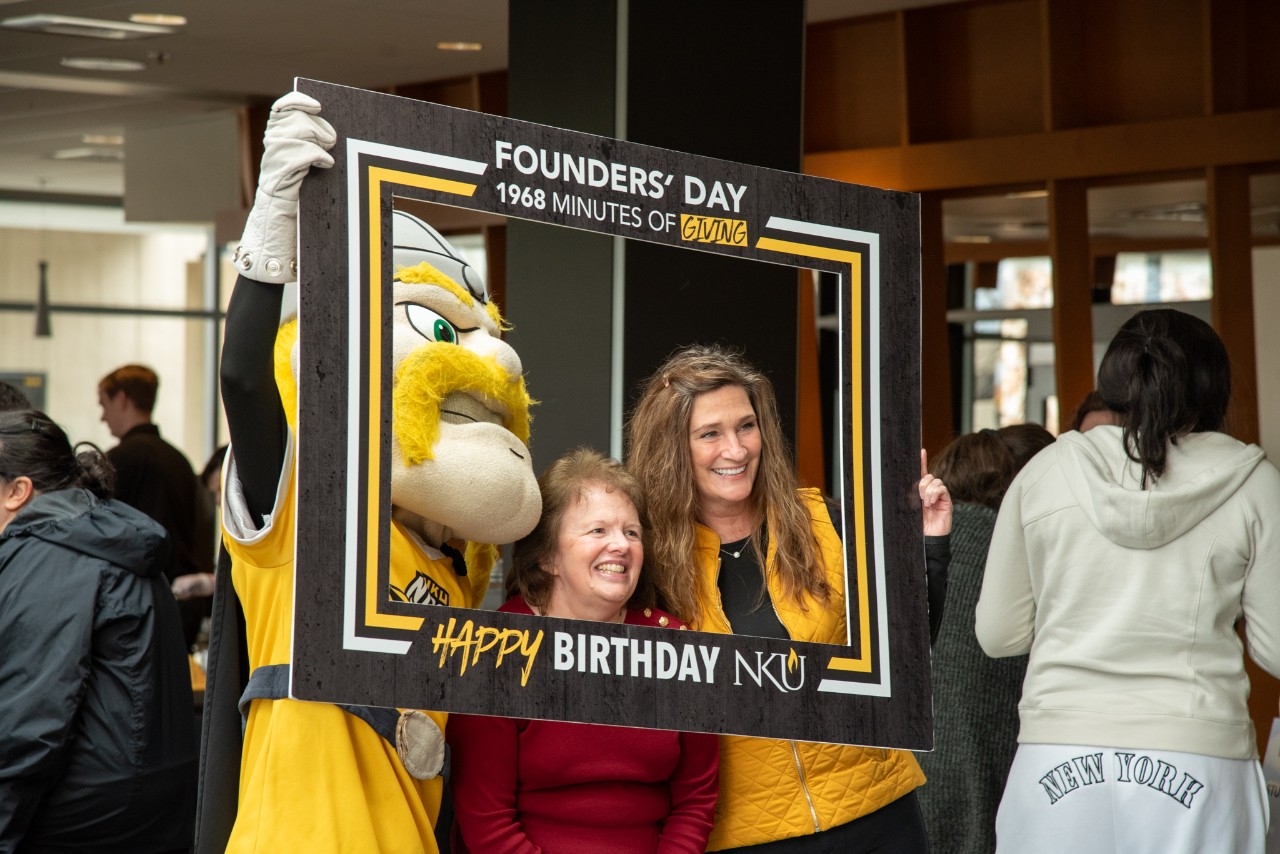 Victor Viking poses with faculty, staff and alumni at the 2025 Founders' Day birthday party.