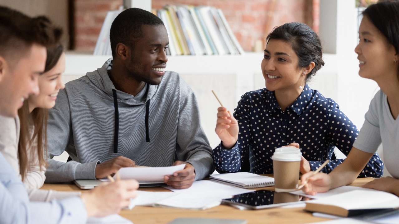 Students talk at a table with books and coffee